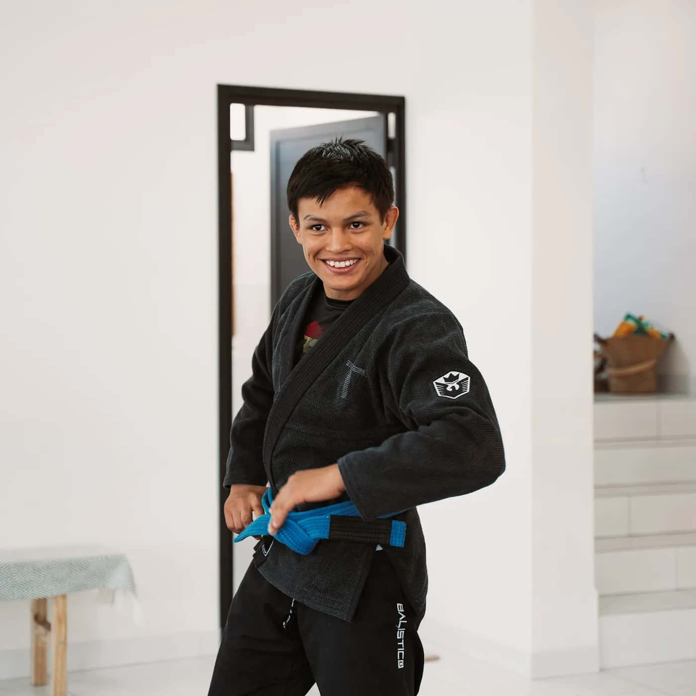 Aluno sorrindo enquanto ajusta a faixa do kimono